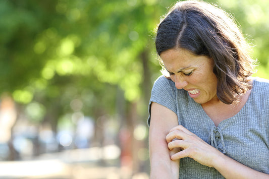 Woman being bitten by a black fly in spring because she is outside weeding during black fly season. She should get a Tertill Weeding robot to avoid being outside in during the buggiest part of the day.